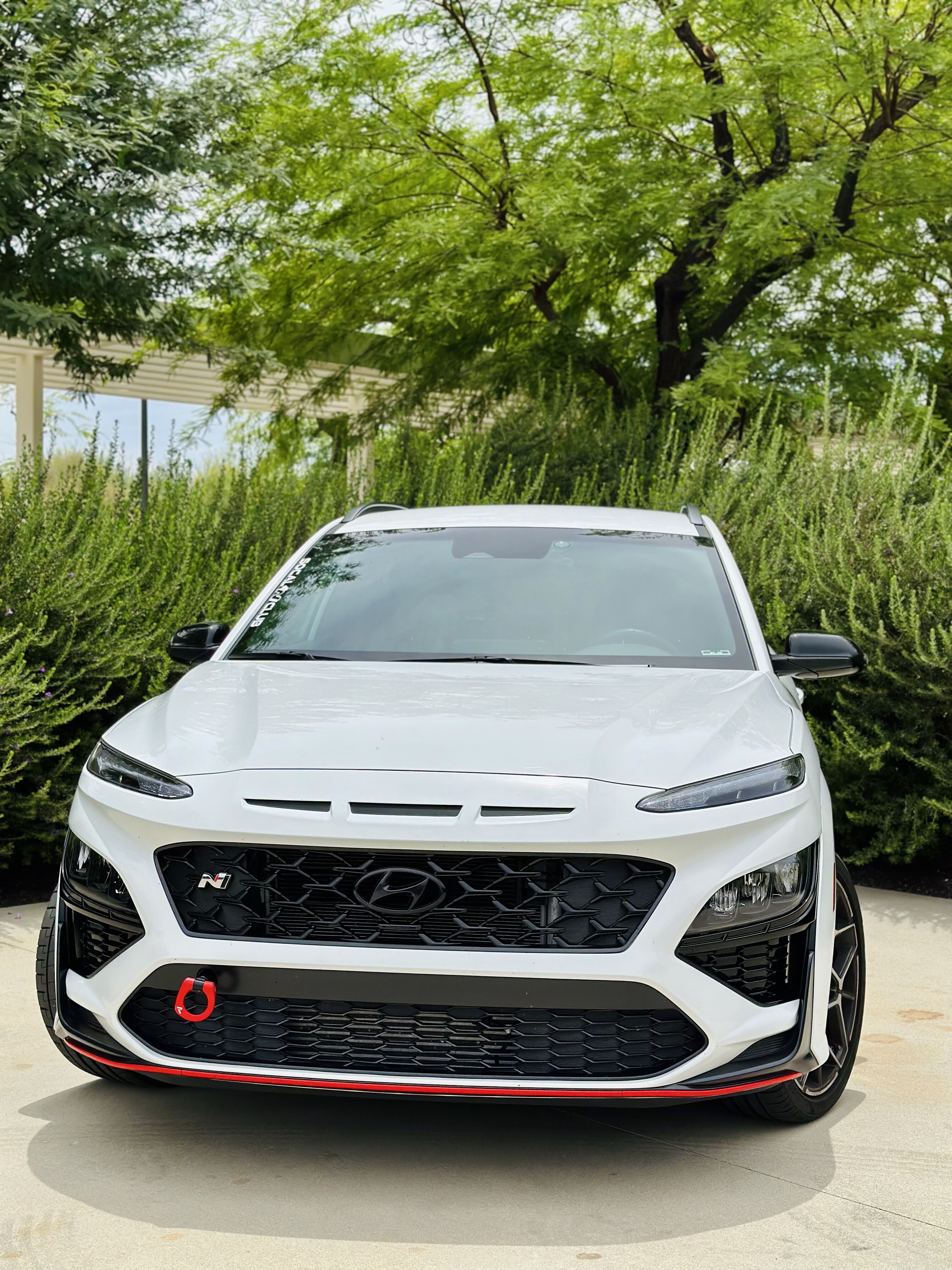 Kona N parked in front of trees and bushes. 