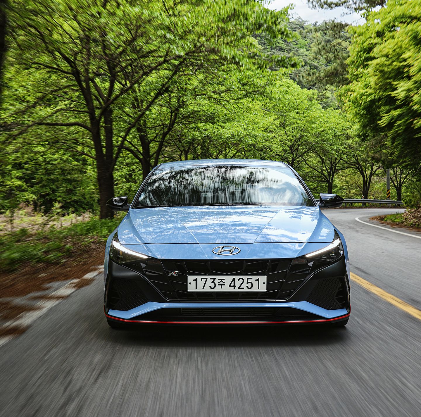 Elantra N vehicle driving on a dense forest road with its front facing up