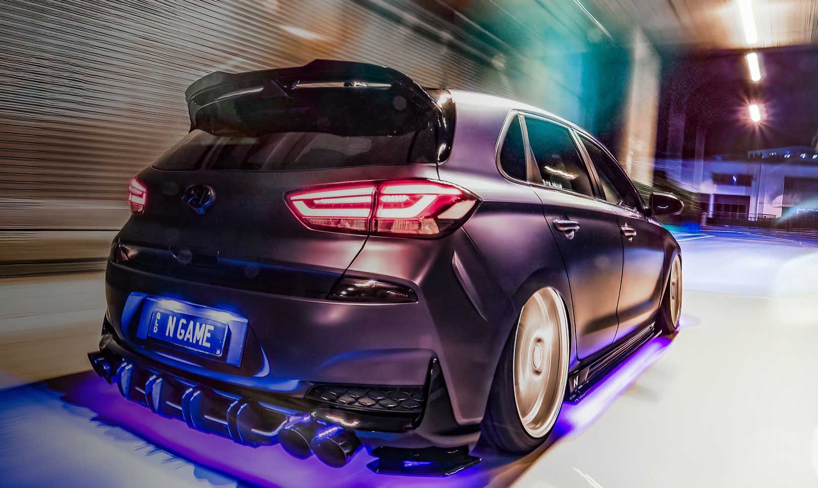 A vehicle is parked in a space illuminated by a neon sign. The rear of the vehicle is visible.