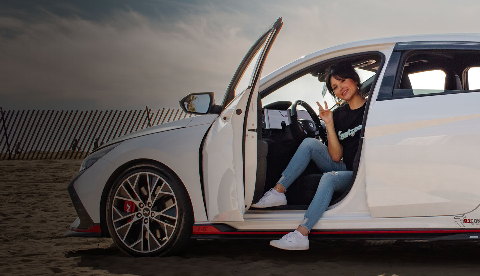 Nfluencer posing while sitting on the driver's seat with the car's door open