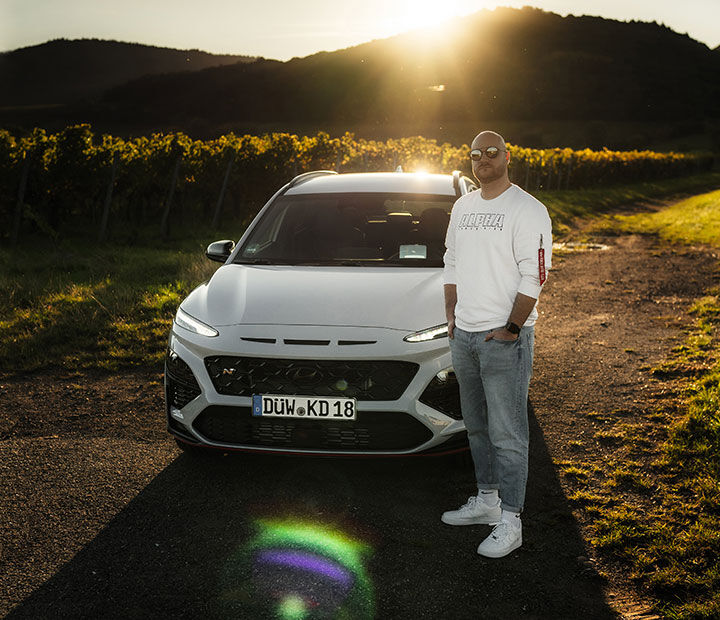 Nfluencer posing in front of the vehicle with the front of the vehicle visible