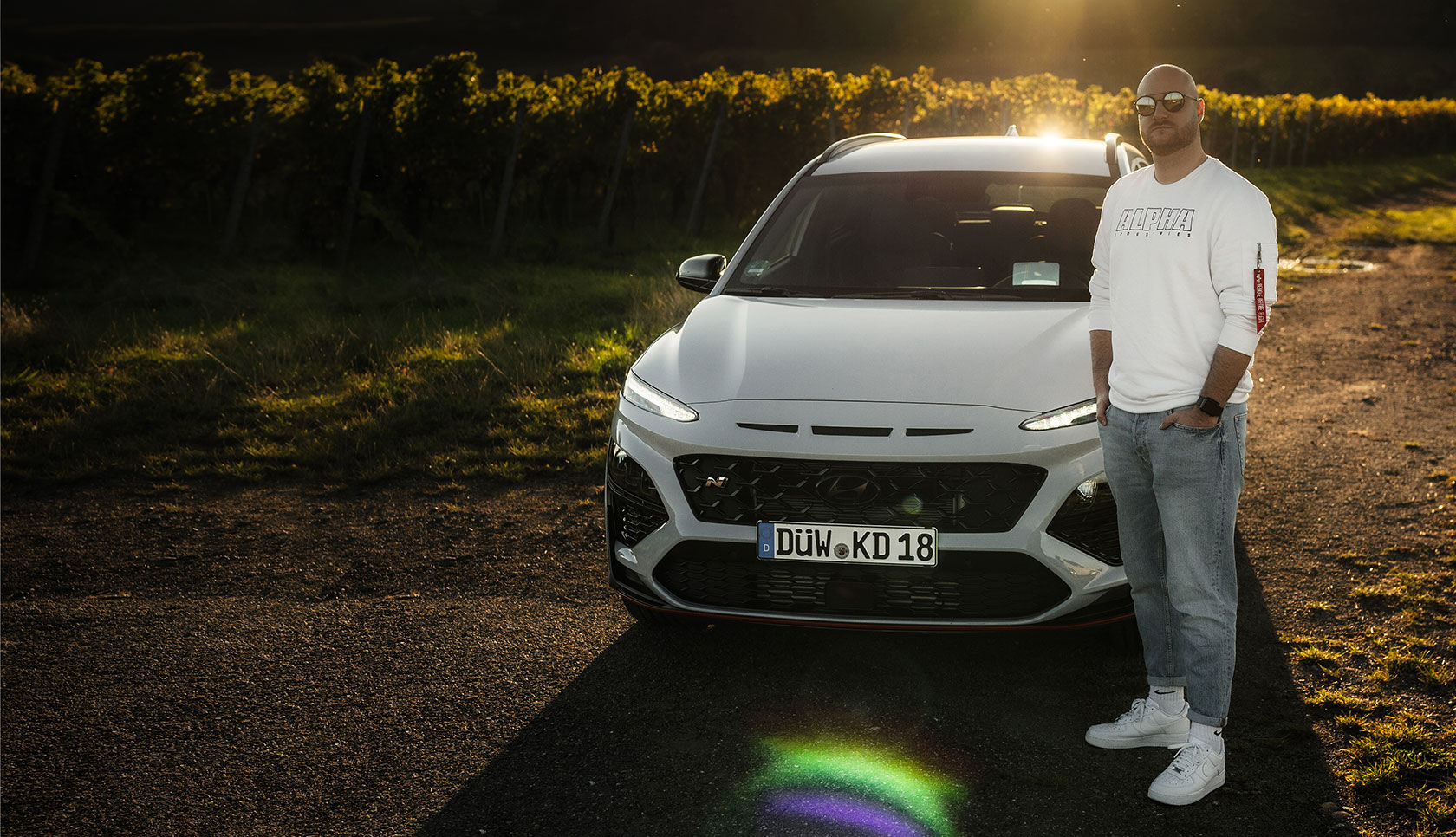 Nfluencer posing in front of the vehicle with the front of the vehicle visible