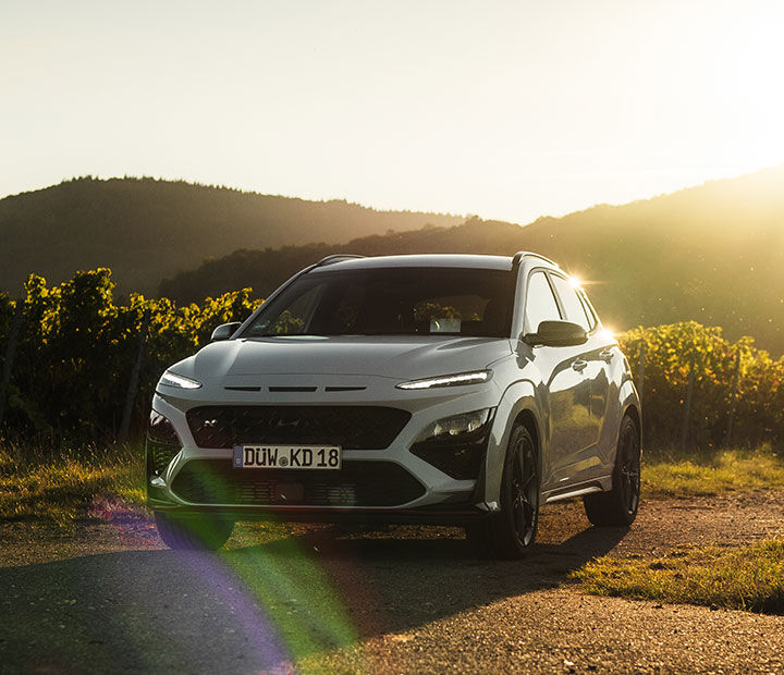 Sunlight shines behind a car parked in a field