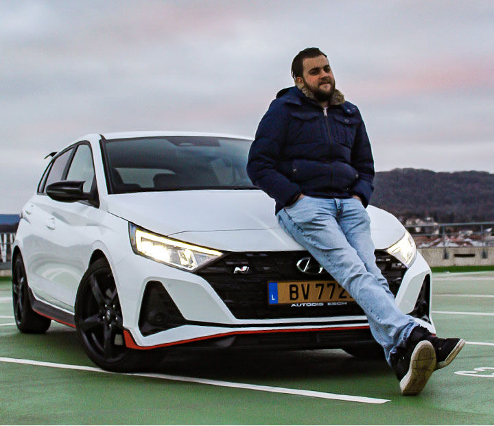 A man poses while sitting on the bonnet of an I20 N