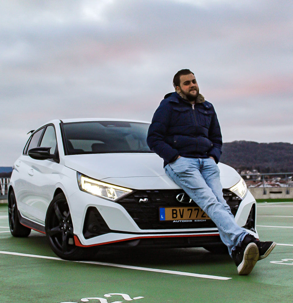 A man poses while sitting on the bonnet of an I20 N