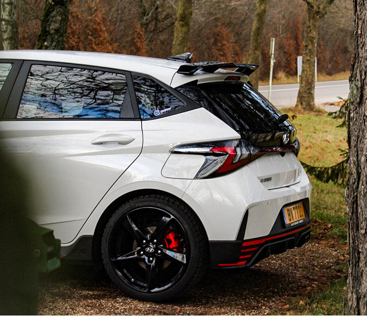 The rear of the i20 N is seen parked between the trees
