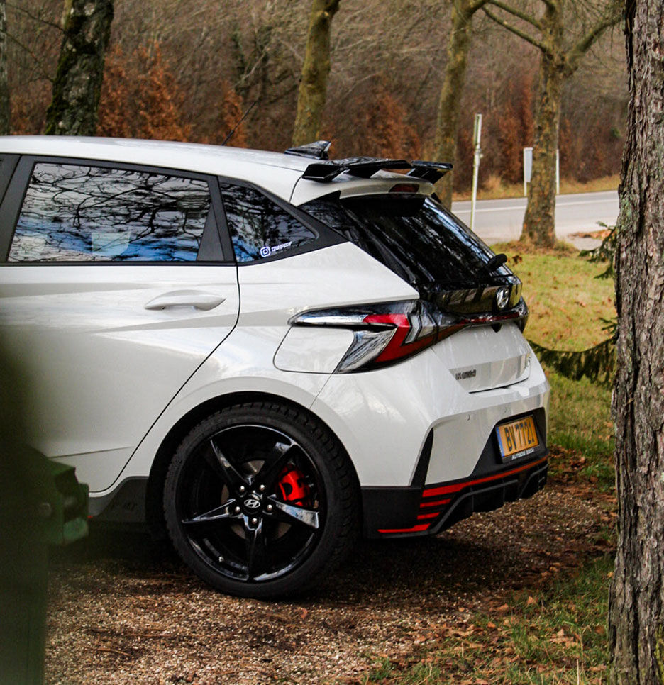 The rear of the i20 N is seen parked between the trees