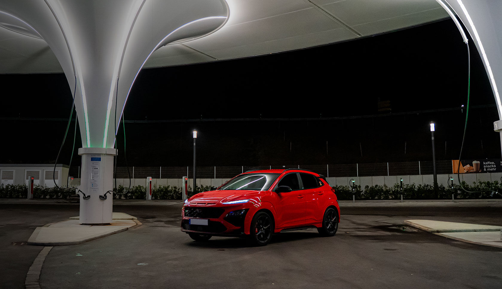 The front of a car is visible, parked in front of a building with lights on