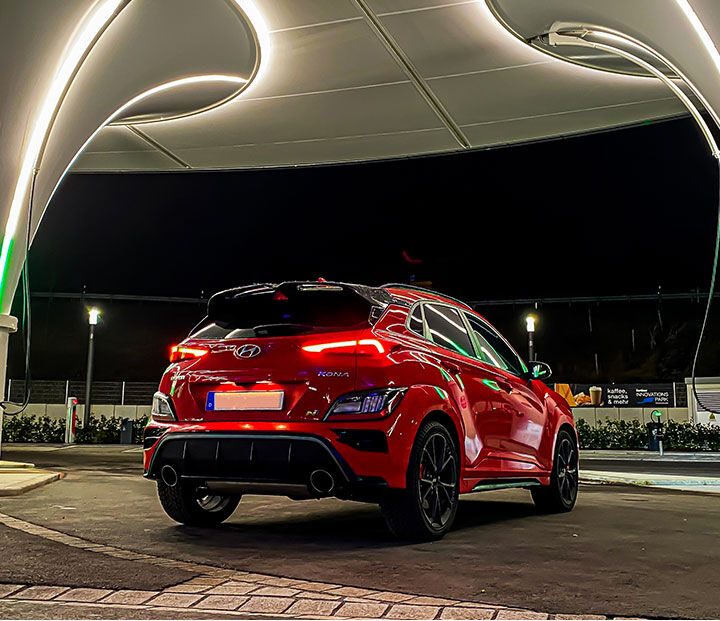 The rear of the car is visible, parked against a building with lights on