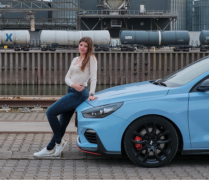 Nfluencer posing on the bonnet of a side-parked car